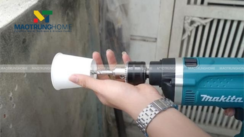 Sử dụng một chiếc ly nhựa hoặc phễu chắn bụi cắt bỏ phần đáy rồi luồn mũi khoan