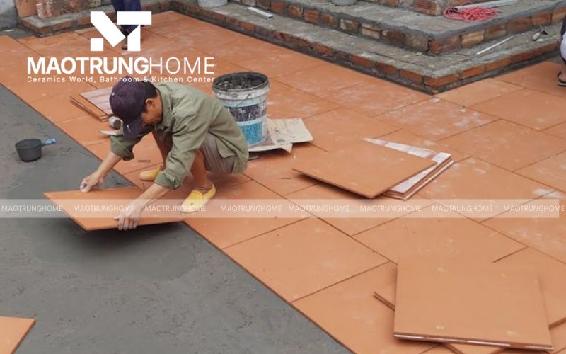 Ban công với gạch giả gỗ tông màu nâu trầm, kết hợp ghế xanh hiện đại.
